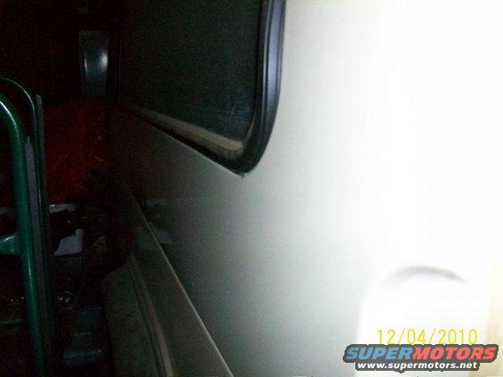Close-up of a vehicle's interior, showing a dark dashboard area and a light-colored door panel