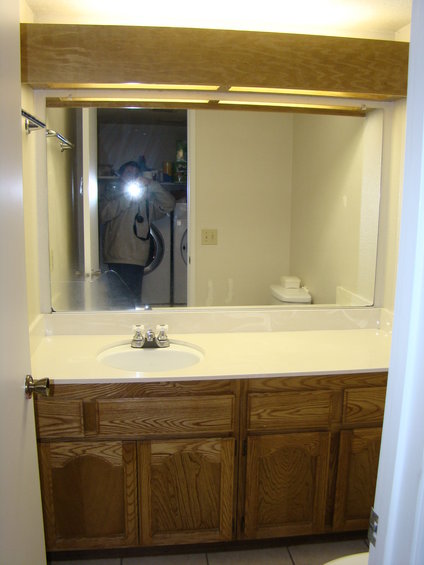 Bathroom vanity with sink and mirror reflecting a person and laundry machines