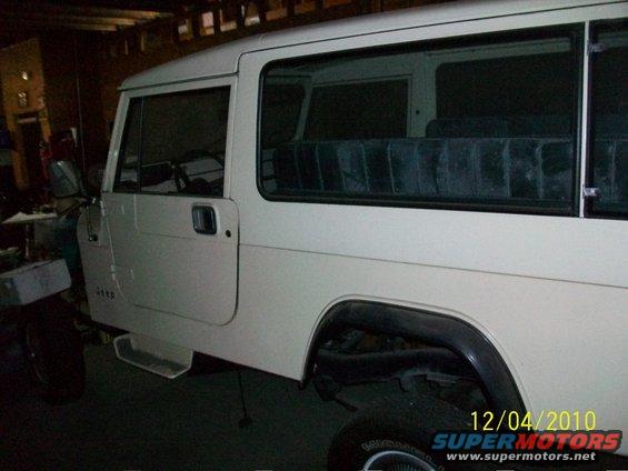 Side view of a white Jeep CJ-8 Scrambler with dark interior seats visible through the windows