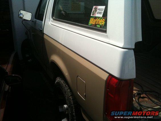 Two-tone Ford Bronco with a Marines sticker on the rear window