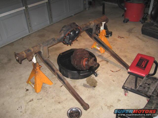 Car rear axle assembly on jack stands with differential removed into a pan