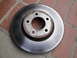 2003 Ford Taurus - Close-up of a used brake rotor, showing wear marks and rust around the hub.