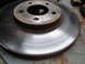 2003 Ford Taurus - A worn and rusted brake rotor sits on a metal surface, showing signs of age and use.