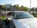 2003 Ford Taurus - A silver sedan is parked in a driveway with a woman sitting beside it.