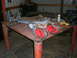 1995 Ford Bronco - Various automotive parts, including suspension components and engine blocks, are laid out on a workbench in a garage setting.