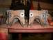 1995 Ford Bronco - Two rusty suspension brackets with rubber bushings sit on a metal table in a workshop.
