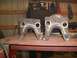 1995 Ford Bronco - Two custom-welded metal brackets are displayed on a workbench, likely for automotive modification.