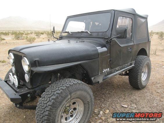 Black Jeep CJ-7 with aftermarket bumpers and side steps, parked in a desert landscape