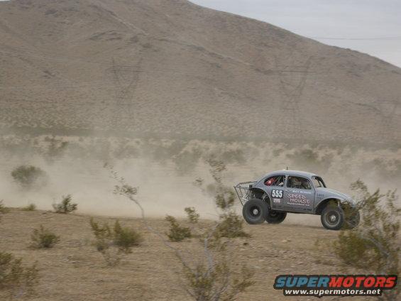 Off-road race car with number 555 on door, mid-air over desert terrain