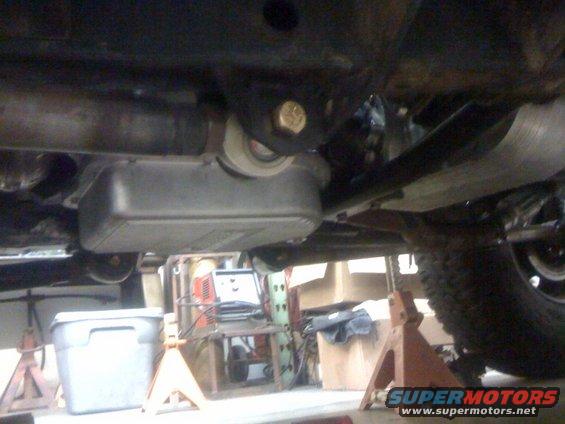 Underside of a vehicle on jack stands, showing the transmission pan and exhaust