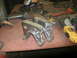 1995 Ford Bronco - Two custom metal brackets sit on a workbench surrounded by tools, suggesting a fabrication or repair project.