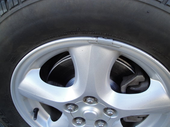 Close-up of a silver 5-spoke wheel with a tire and brake rotor visible