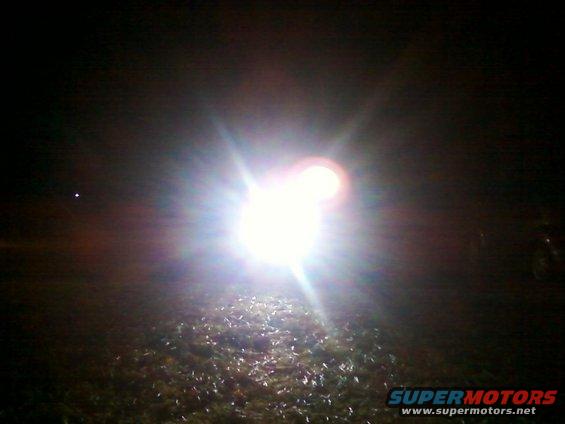 Bright headlight beam shining into the dark, illuminating the ground