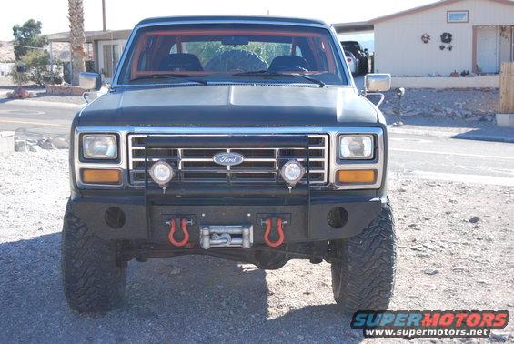 Front view of a dark-colored Ford Bronco with a winch and tow hooks on the bumper