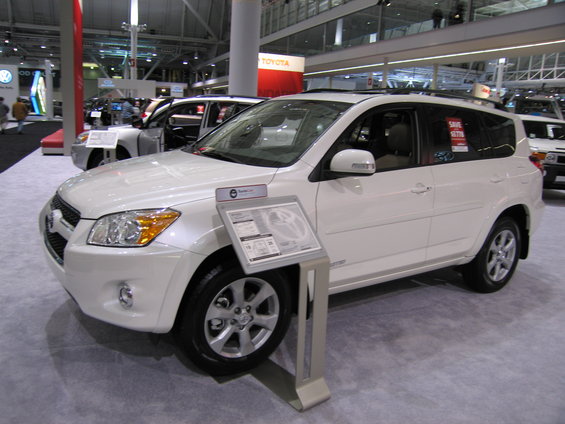 White SUV on display at an auto show with a sign in front of it
