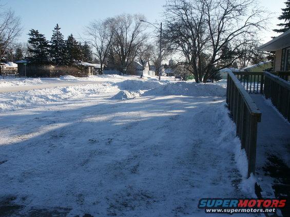 Snowy driveway in front of a house with a wooden ramp on the right