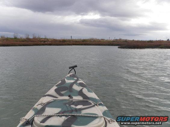 Camouflaged kayak on water under cloudy sky
