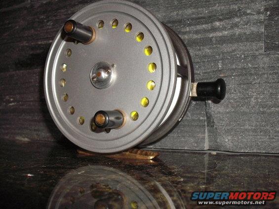 Silver fishing reel with black handle and yellow accents
