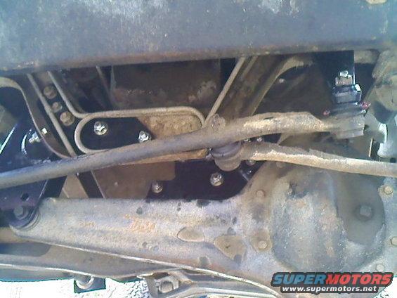 Underside view of truck suspension and steering components. Shows tie rods, ball joints, and frame