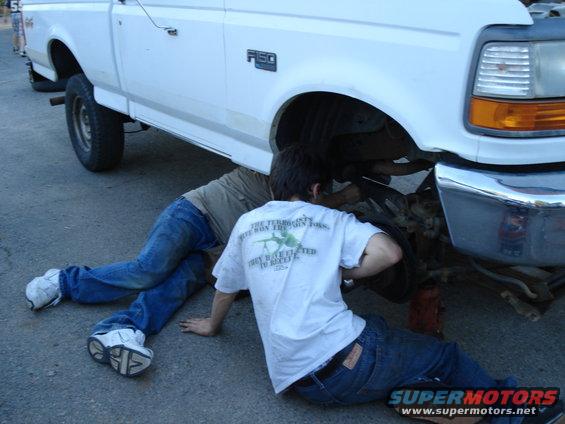 1995 Ford F-150 front wheel area with two people working on it
