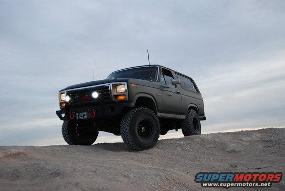 Gray 1982 Ford Bronco with off-road tires and winch on a dirt hill