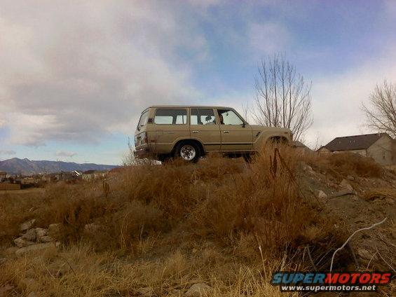 Tan 1980s Toyota Land Cruiser parked on a grassy hill