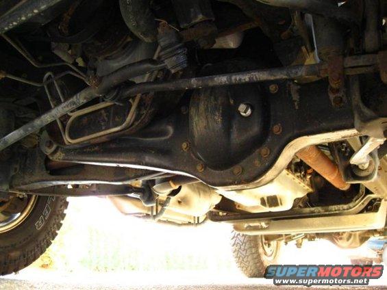 Undercarriage view of a vehicle's differential and suspension components. Some rust is visible on exhaust pipe