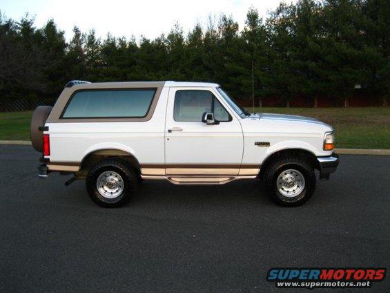 White 1996 Ford Bronco side view with brown trim and spare tire