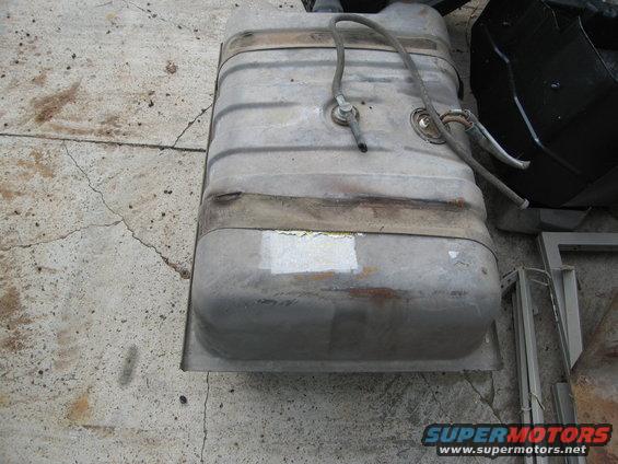 Metal gas tank with fuel lines attached, sitting on concrete