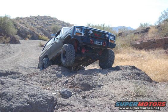 Dark green SUV with lifted suspension and large tires navigating a rocky, off-road trail