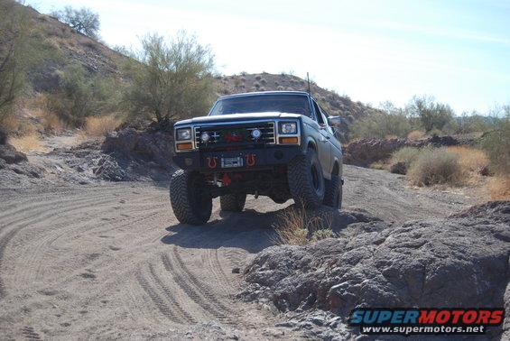 Modified dark pickup truck on rocky, dusty trail