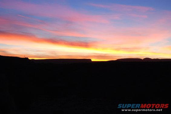 Sunset over desert landscape with colorful sky and silhouetted mesas