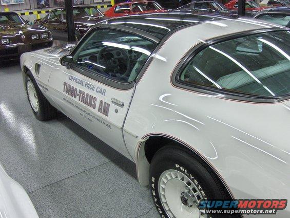 White 1980 Pontiac Turbo Trans Am Pace Car with 'OFFICIAL PACE CAR TURBO-TRANS AM' text on the door, parked indoors with other cars