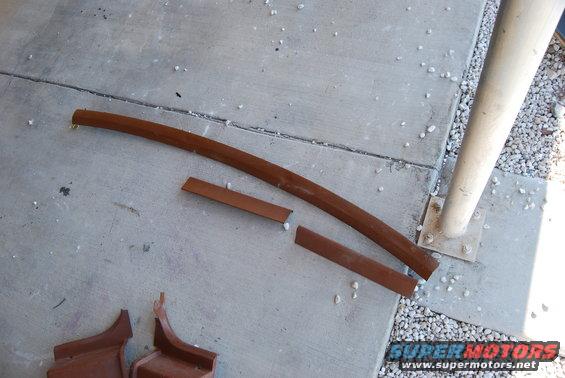 Two brown metal trim pieces and two curved pieces on concrete