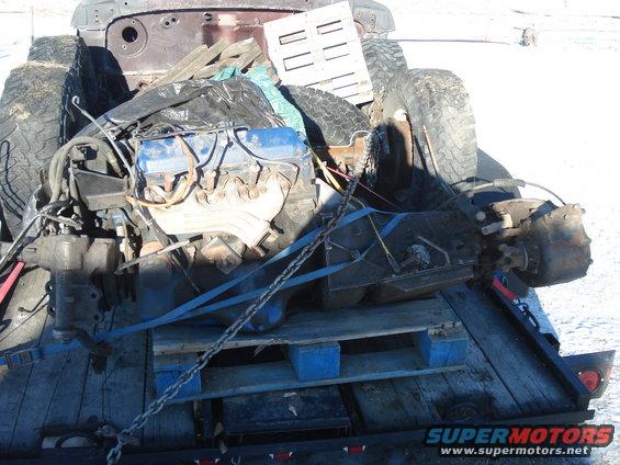Engine, tires, and other parts loaded onto a trailer with wooden pallets
