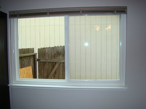 Sliding window looking out at a wooden fence and siding
