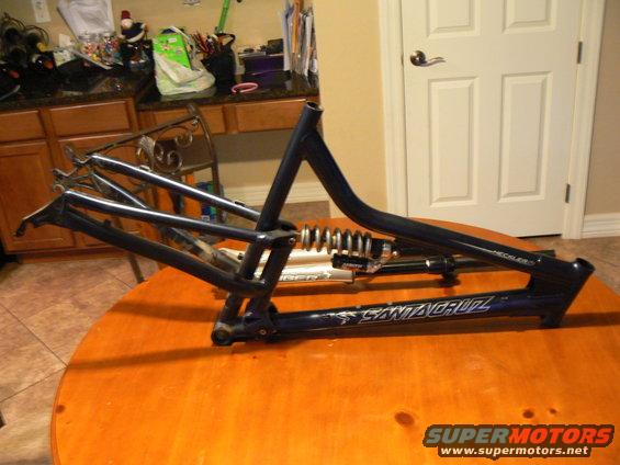 Blue Santa Cruz bicycle frame with rear shock absorber on an orange table