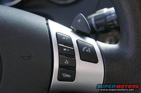 Close-up of steering wheel buttons, including volume, track change, and phone controls
