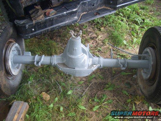 rear axle assembly with driveshaft yoke, sitting on grass next to truck bed