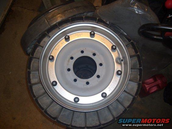Close-up of a truck wheel with visible text markings, stacked on a tire