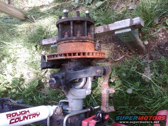 Rusty front axle assembly with brake rotor and 'Rough Country' shock absorber