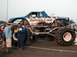 1994 Ford Bronco - A monster truck named "Equalizer" with flame graphics and the number 33 is displayed at an event.