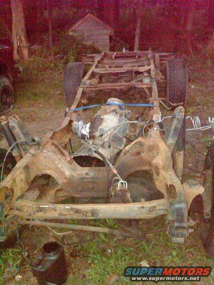 rusted truck frame with engine and suspension parts visible, outdoors