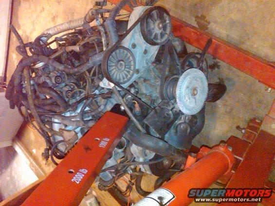 Engine assembly with belts and pulleys, supported by an engine hoist