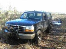 Black Ford Bronco parked on a dirt road with brush around it