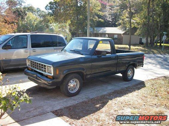 Dark blue pickup truck parked on driveway, front 3/4 view. Visible grille and bumper