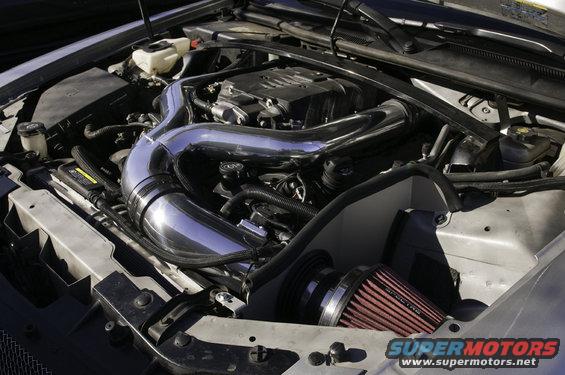 Engine bay with chrome intake tube and red air filter. Supermotors.net logo visible