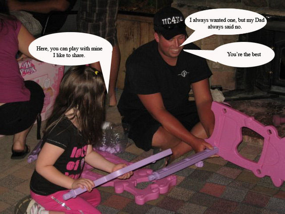 Man and girl assemble pink toy structure. Man wears black t-shirt and cap with "11C4X4" text. Girl wears pink pants and black shirt with pink text
