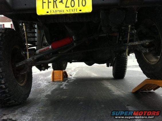 Undercarriage of a lifted vehicle with large tires and a yellow license plate reading FFR-2610