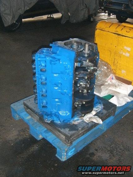 blue engine block and crankshaft assembly on a wooden pallet